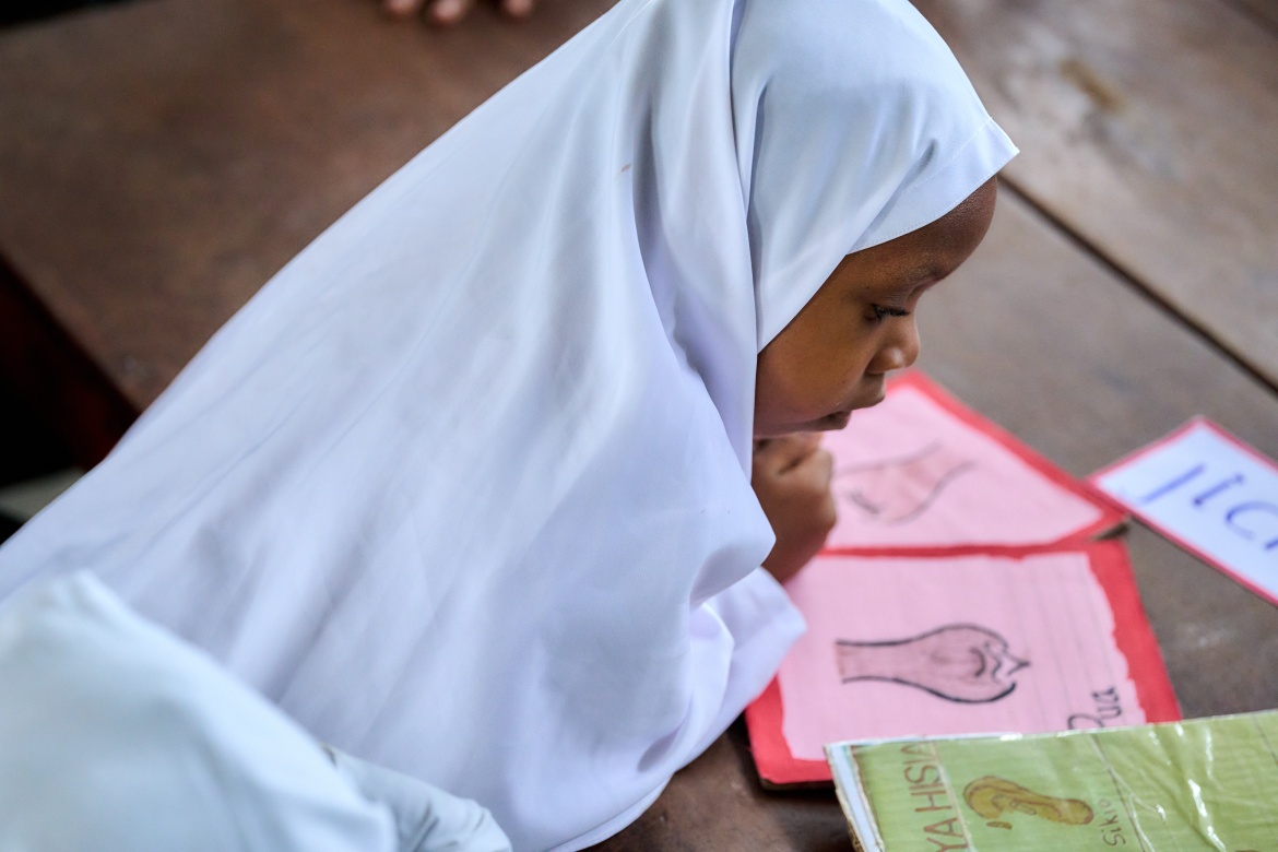 Une élève de 2e année de maternelle regarde des cartes illustrées pendant un cours au Centre TuTu de Kikaangoni, à Zanzibar.