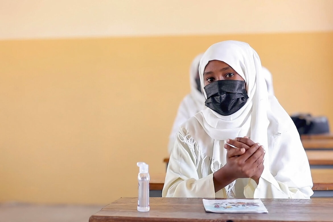 A young student uses hand sanitizing gel in class. Sudan, July 2021